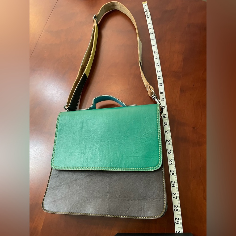 Leather color block shoulder bag with short handle and adjustable leather strap.